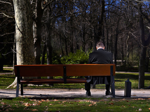 Businessman sat in a bench, looking towards to down