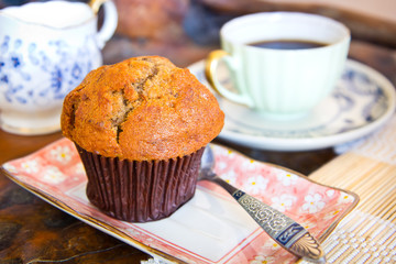 Banana muffin and a cup of coffee on wooden table