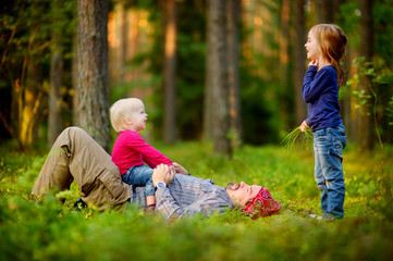 Naklejka na ściany i meble Young father and his little daughters in forest