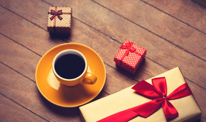Cup of coffee and gift box on a wooden table.