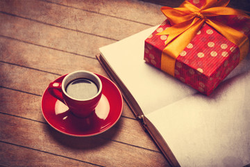 Cup of coffee and gift box with book on a wooden table