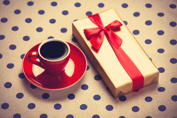 Cup of coffee and gift box on a polka dot background.