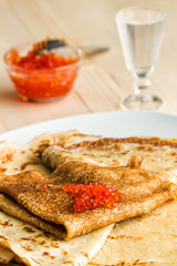 Russian pancakes with red caviar and glass of vodka glass on the