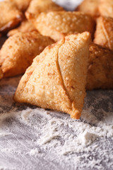 pile of baking samosas on a floured table. Vertical