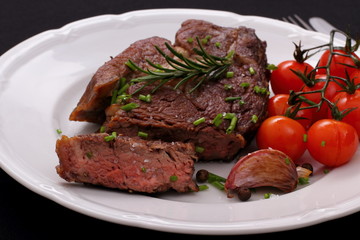 Rib eye steak with garlic, cherry tomatoes, herbs