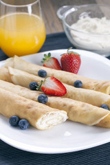 Delicious sweet rolled pancakes on a plate with fresh fruits