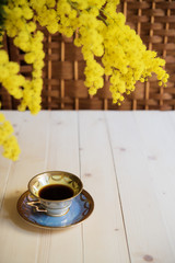 Cup of coffee on wooden table and mimosa