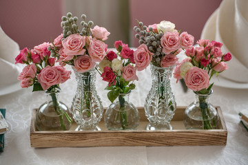 Five bouquets of roses on a festive wedding table in the restaur