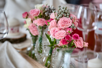 Bouquets of roses on a festive wedding table in the restaurant.