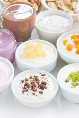 Fototapeta na wymiar Assorted fruit yoghurts and breakfast ingredients, vertical