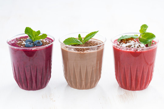 chocolate, blueberry and strawberry milkshakes in glasses