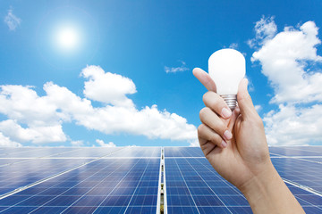 Solar energy panels and Light bulb in hand, Green energy concept