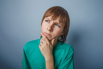 boy teenager European appearance brown hair in a shirt on a gray