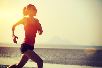 young woman running on sunrise beach