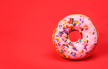 Donut with sprinkles over red background