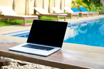 Vacation work with laptop on bench at pool
