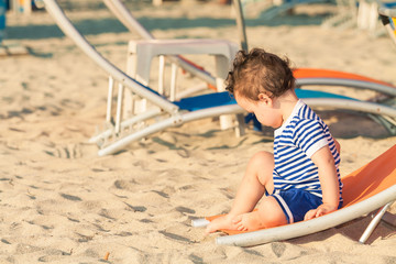 Toddler dressed as a sailor sitting on a tilted sunbed and explo