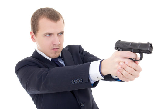 young man in business suit shooting with gun isolated on white