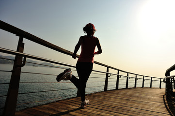 young fitness woman running on seaside boardwalk