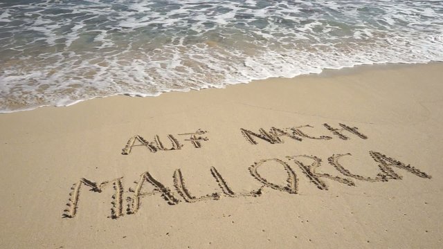 Text AUF NACH MALLORCA in Sandstrand gezeichnet