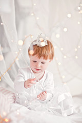 Fototapeta premium Beautiful lcute red-haired girl sits in white bed. Princess bed.