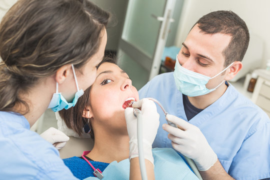Dentist and dental assistant examining patient teeth