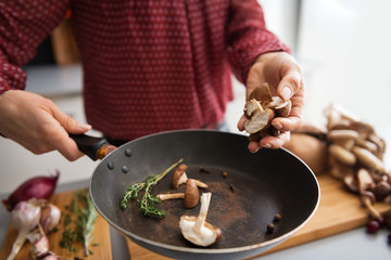 Closeup on young housewife cooking mushrooms