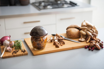Closeup on jar of pickled mushroom on cutting board