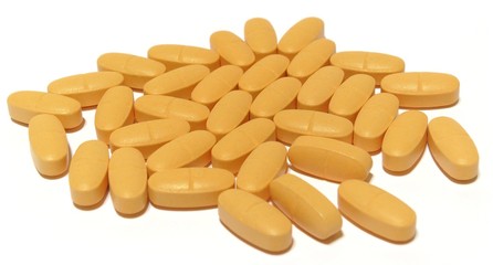 Yellow pills on white background, shallow DOF