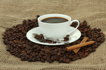 cup with coffee beans on sackcloth