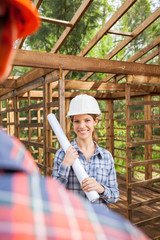 Obraz na płótnie Canvas Happy Female Architect Holding Blueprint At Construction Site
