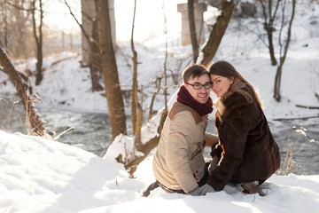 Fototapeta premium Cheerful couple in a pine forest in winter