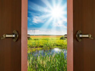 open door with a view of green meadow illuminated by bright suns