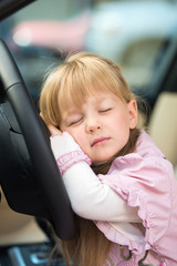 Little girl sleeping on car steering wheel