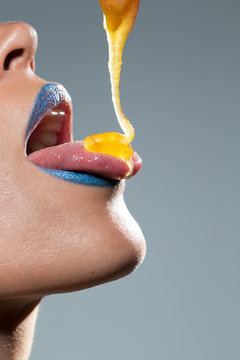 Woman dripping honey on her tongue