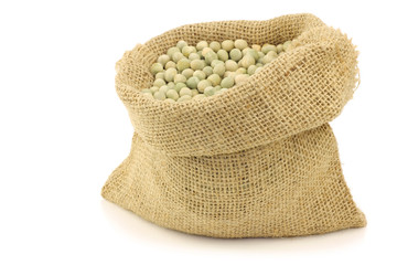 Green peas in a burlap bag on a white background