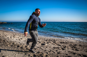 Running man jogging on beach.