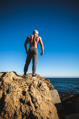 Man stands on a rock by the sea against the sky