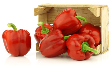 red bell peppers (capsicum) in a wooden crate on a white backgro