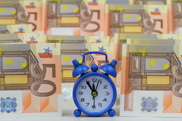 Miniature clock with banknotes in the background