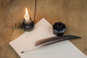 Quill pen and inkwell, and candlestick well resting on old paper