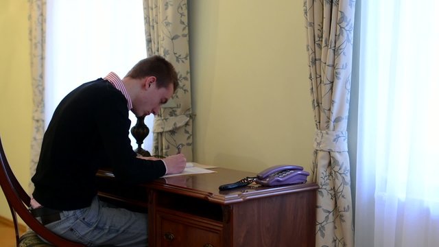 man works at a desk - writing