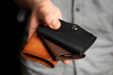 Man holding hand made leather wallets on black background