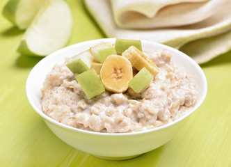 Oatmeal porridge with apple and bananas slices