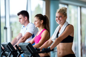 Fototapeta premium friends exercising on a treadmill at the bright modern gym