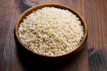 raw rice in wood bowl on wood table