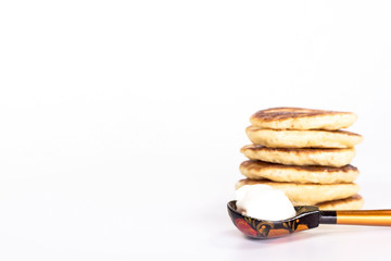 isolated stack of pancake and wooden spoon with sour cream