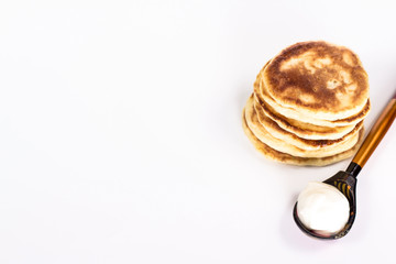 isolated stack of pancake and wooden spoon with sour cream