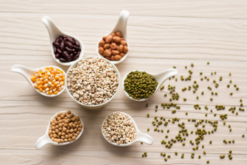 Different kinds of bean seeds, lentil, peas in dish on wooden ta