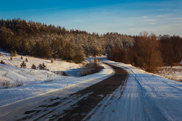 Obraz premium beautiful winter road through snowy fields,sunset and forests